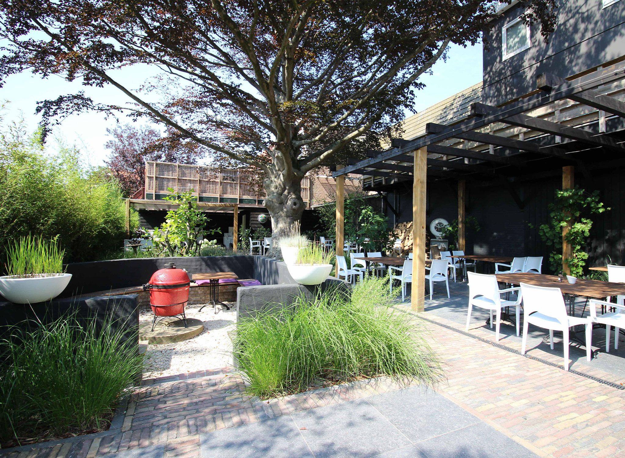 An outdoor patio area with a barbecue grill, seating arrangements, and a pergola structure.