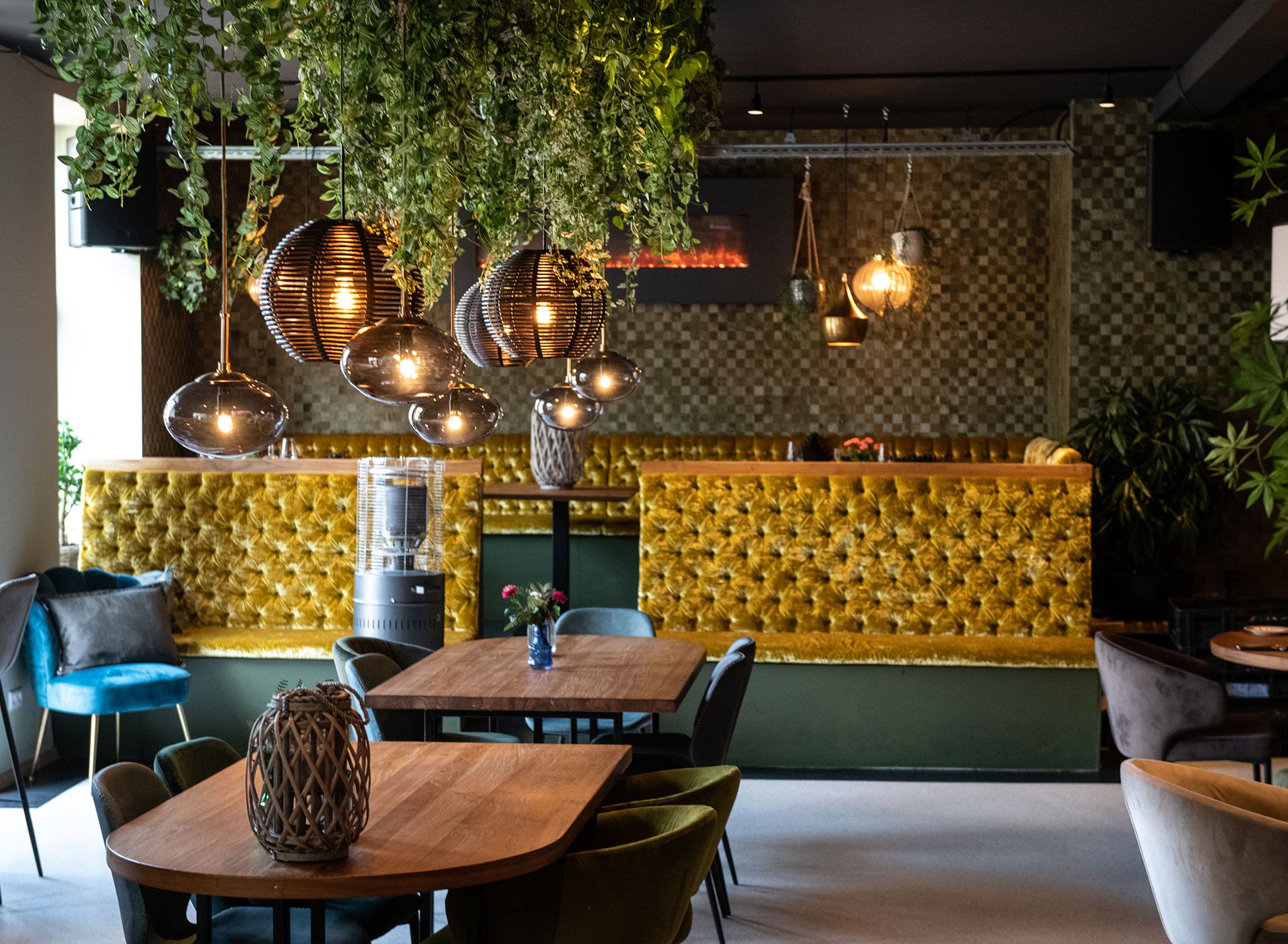 A restaurant interior with a bar area, hanging lights, and upholstered seating.