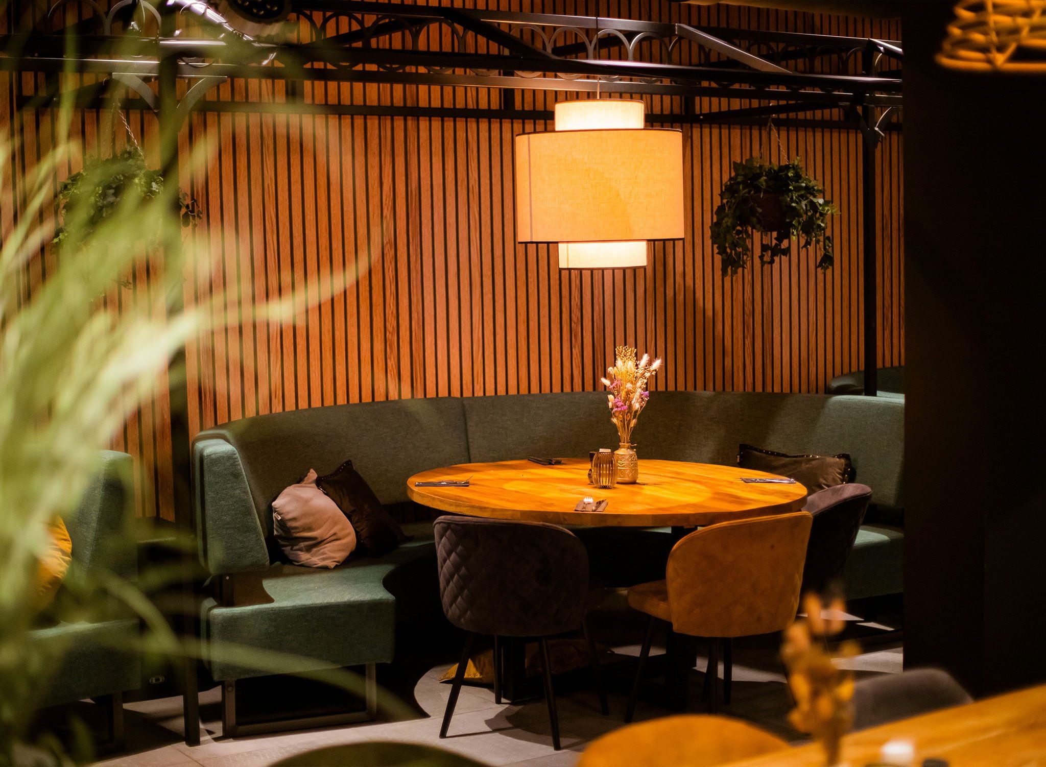 A cozy seating area with a round wooden table, cushioned chairs, and a hanging lamp.