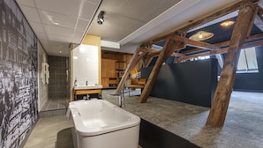 A modern bathroom with a large bathtub, wooden beams, and a tiled shower area. - Fletcher Hotel-Restaurant Marktstad-Schagen (Schagen)