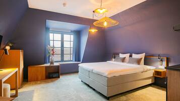 A modern bedroom with a large bed, a window with curtains, and a unique ceiling design.