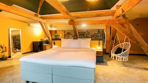 A bedroom with a large bed, wooden beams, a hanging chair, and a cityscape wall. - Fletcher Hotel-Restaurant Marktstad-Schagen (Schagen)