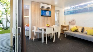Une chambre moderne comprenant un coin repas, un canapé et un téléviseur fixé au mur.