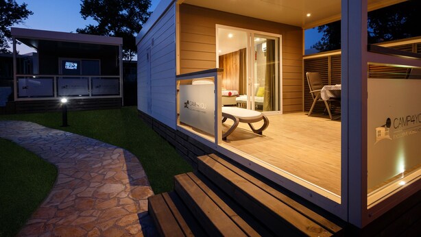 Un espace extérieur moderne et bien éclairé, avec un chemin de pierre menant à une terrasse en bois.