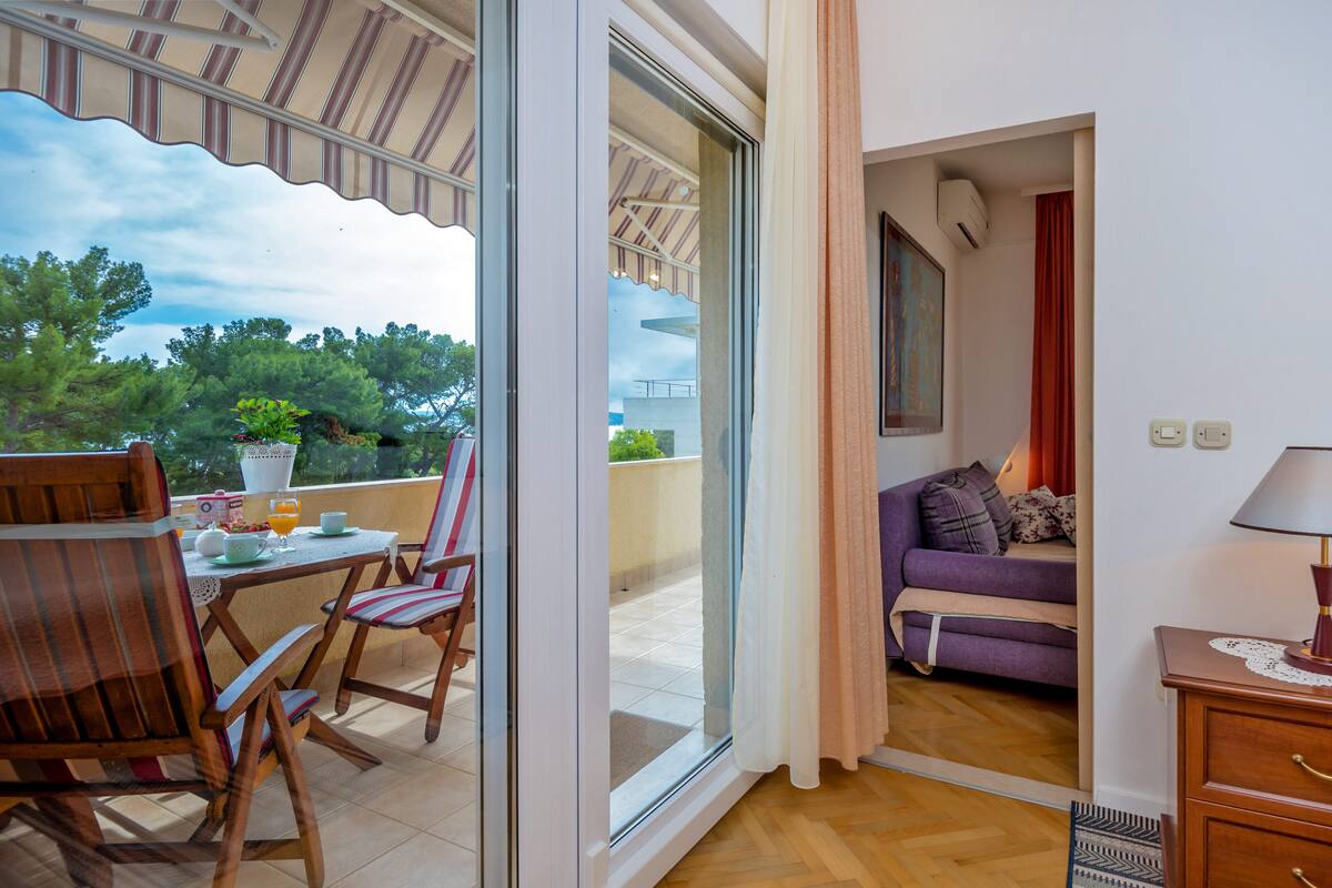 A balcony with a table and chairs, a sofa, and a lamp.