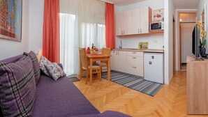 Un espacio habitable compacto con sofá, mesa de comedor y kitchenette.