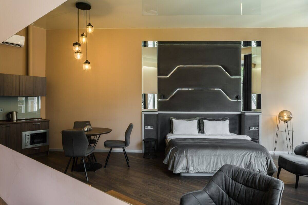 Una habitación de hotel moderna con cama, zona de comedor y kitchenette.
