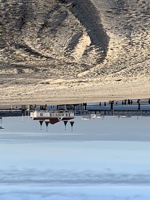 Ein Hotel am Wasser mit einer Pier, die sich ins Wasser erstreckt, mit mehreren Balkonen und freiem Blick auf die umliegenden Klippen.
