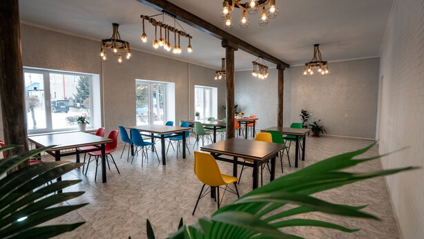 A spacious dining area with multiple tables and chairs, large windows, and hanging light fixtures. - MIxx Hotel (Karakol)