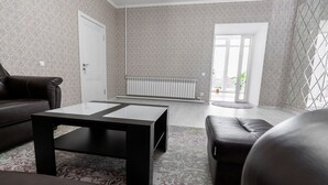 A living room with a black coffee table, a brown leather sofa, and a patterned rug. - MIxx Hotel (Karakol)