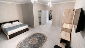 A bedroom with a bed, a rug, a wardrobe, and a mirror. - MIxx Hotel (Karakol)