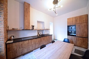 A modern kitchen with wooden cabinets, a black countertop, and a dining area with a wooden table and chairs.
