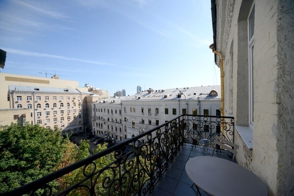 A balcony with a metal railing overlooking a cityscape with multiple buildings.