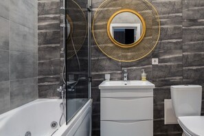 A modern bathroom with a bathtub, a vanity with a mirror, and a toilet. - KievApts Pushkinskaya 10 (Kyiv)