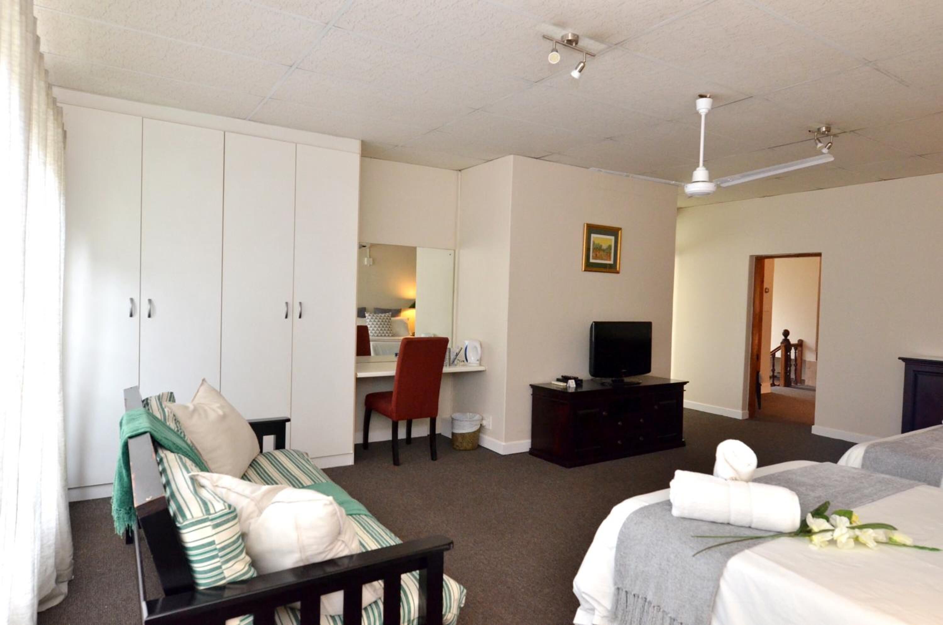A hotel room with a bed, a desk, a chair, a television, and a wardrobe.