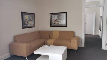 Un salon moderne avec un canapé d’angle beige, une table basse blanche et deux tableaux encadrés accrochés au mur.
