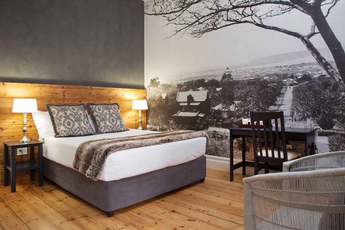 A bedroom with a large bed, two bedside lamps, a chair, and a wicker chair.