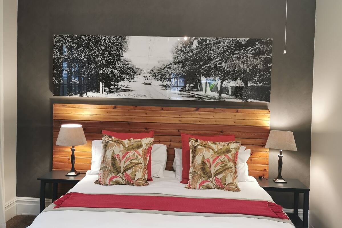 A hotel room with a large bed, two nightstands, a wooden headboard, and a large framed picture on the wall.