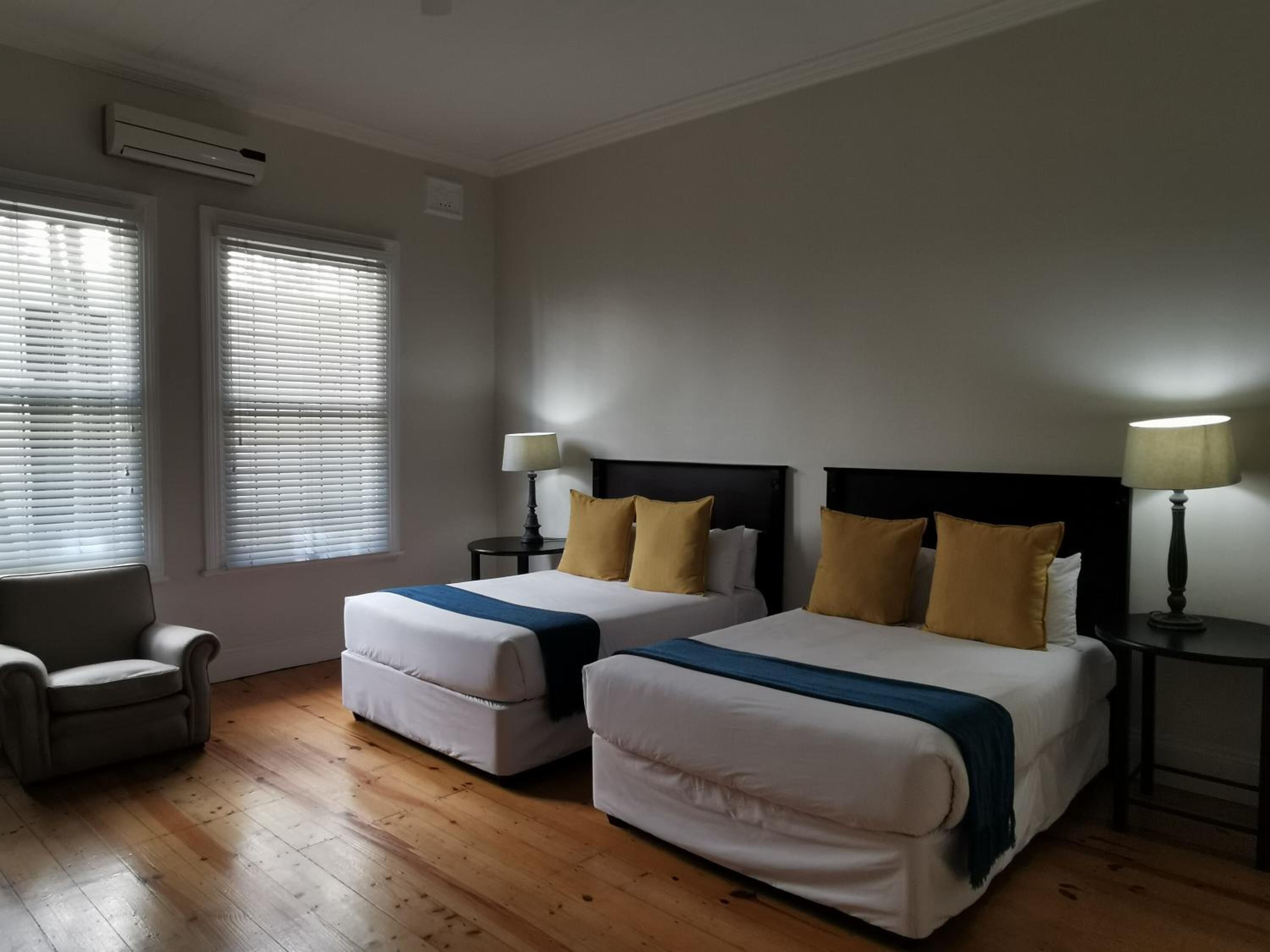 A hotel room with two beds, a chair, and a small table.