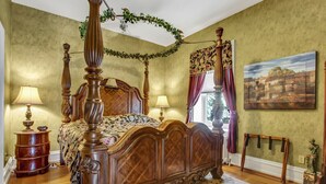 Una cama con dosel, un aparador de madera y un cuadro en la pared.