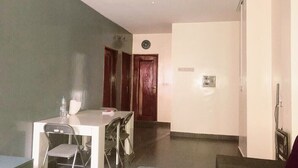 Une pièce dotée d’un ventilateur de plafond, d’une table à manger avec des chaises, d’une horloge au mur et d’une porte donnant sur une autre pièce.