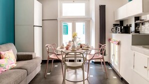 A compact living space with a dining area, kitchenette, and a sofa with a colorful pillow. - Ravecca Luxury apartment in the heart of the centre - 2 bedrooms (GENOVA)