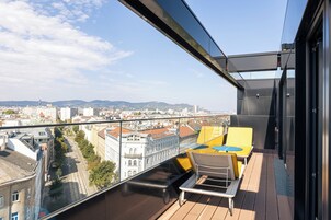 Uma varanda com vista para a cidade, uma cadeira amarela e uma cadeira branca.