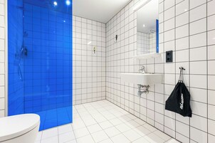 Une salle de bain moderne avec des carreaux blancs et bleus, des toilettes, un lavabo et une douche.
