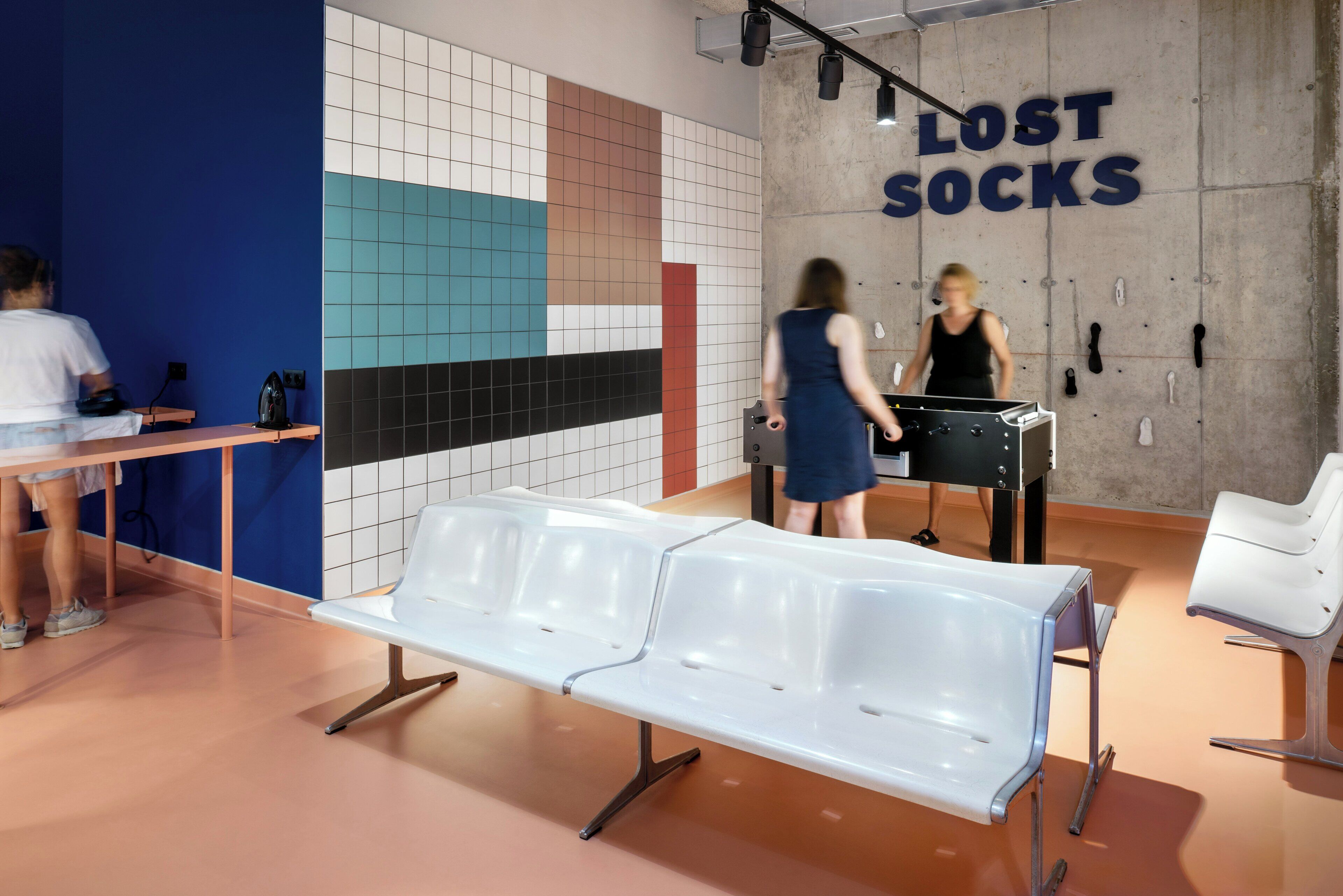 Un área de espera con un banco, una pared con el letrero 'LOST SOCKS' y un zapatero.