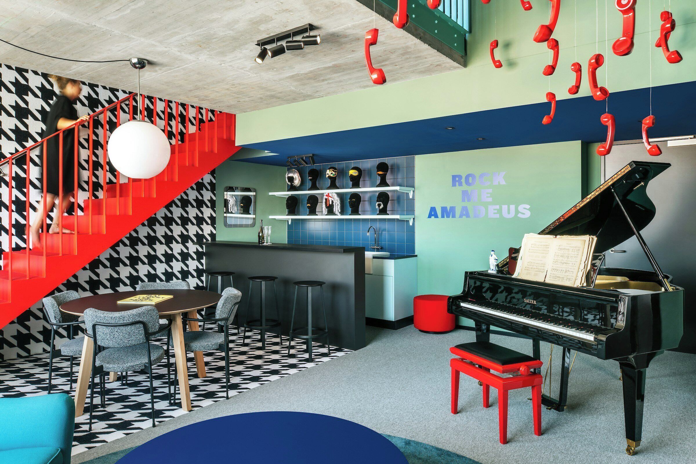 A room with a piano, a bar area, and a staircase.