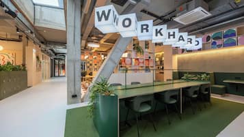 A modern workspace with a glass table, green carpet, and a sign spelling 'WORKHARD'.