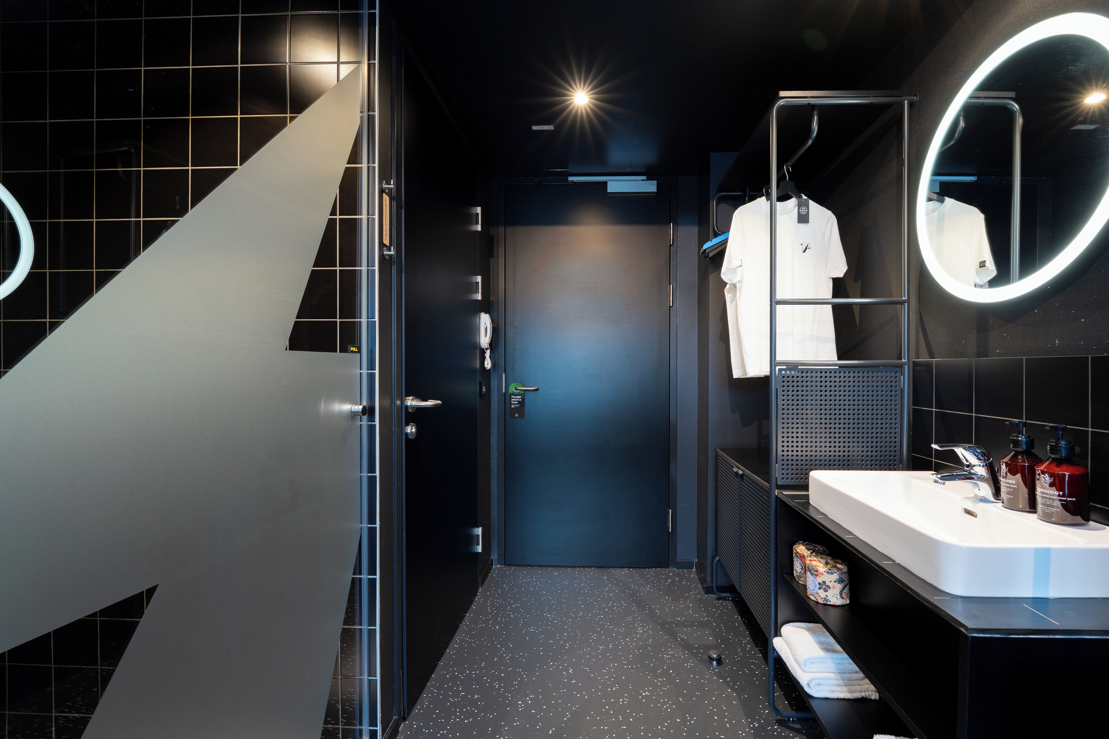 A modern bathroom with a large mirror, a sink, and a towel rack.