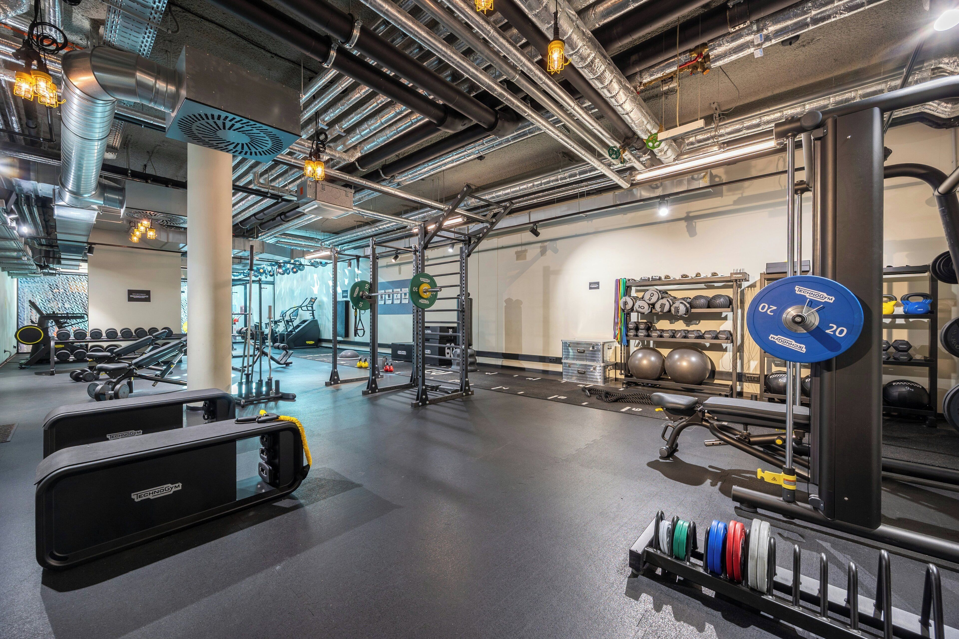 Uma academia com equipamentos de musculação, esteiras e diversos aparelhos de ginástica.