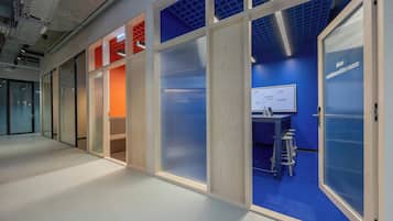 An office space with a collaboration room, a whiteboard, and a blue carpet.