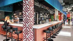Uma área de bar com um balcão comprido, vários bancos e uma parede estampada.