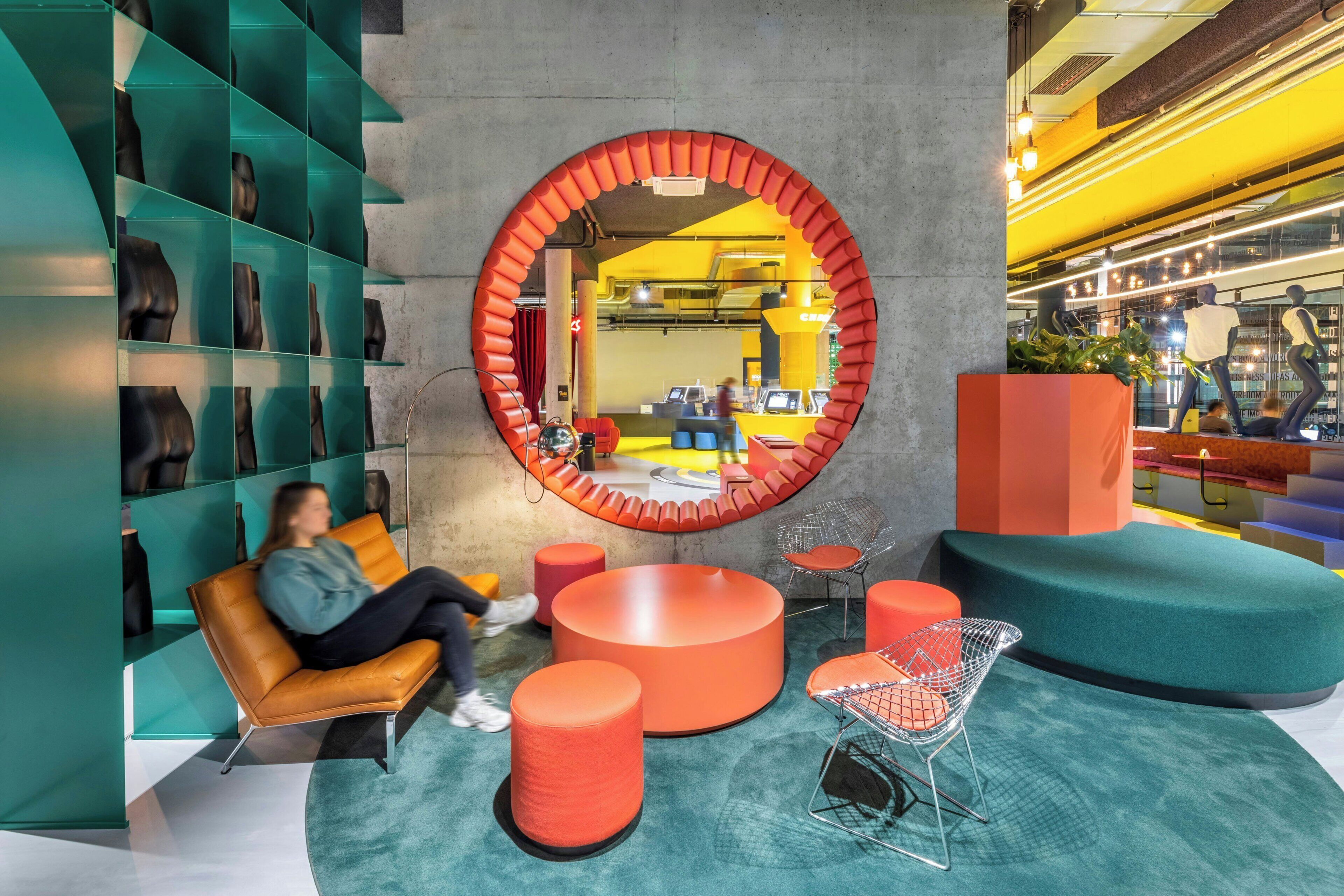 A modern interior with a circular mirror, seating areas, and a display of shoes.