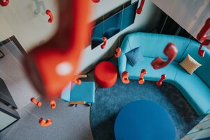 Um interior moderno com um sofá azul, detalhes vermelhos e uma janela grande.
