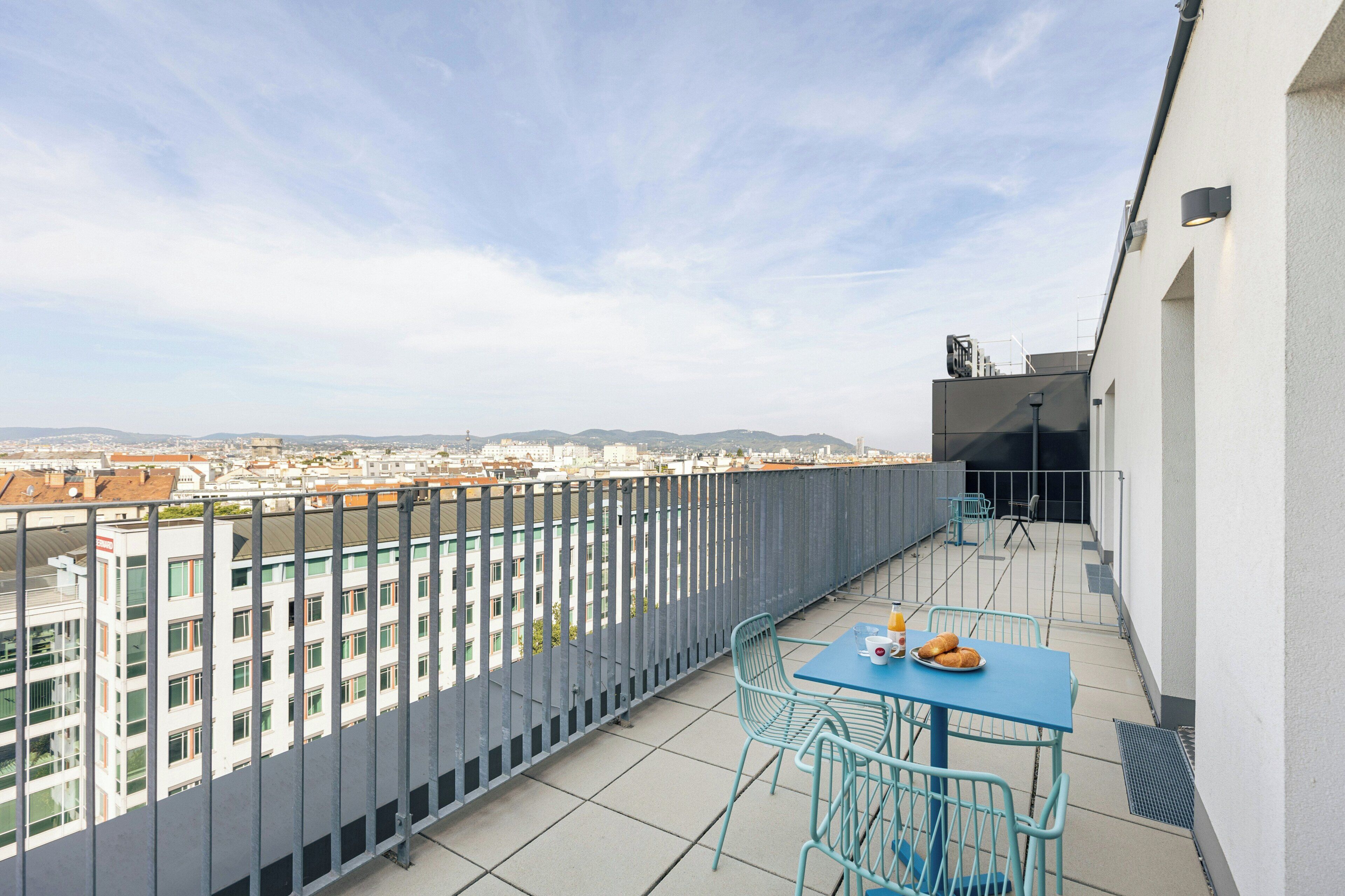 Un balcón con mesa y sillas, con vistas a un paisaje urbano.