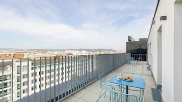 Un balcón con mesa y sillas, con vistas a un paisaje urbano.