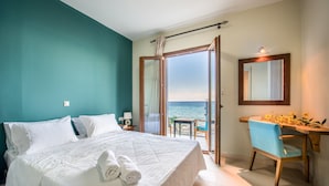 Un dormitorio con cama, escritorio, silla y vista al mar.