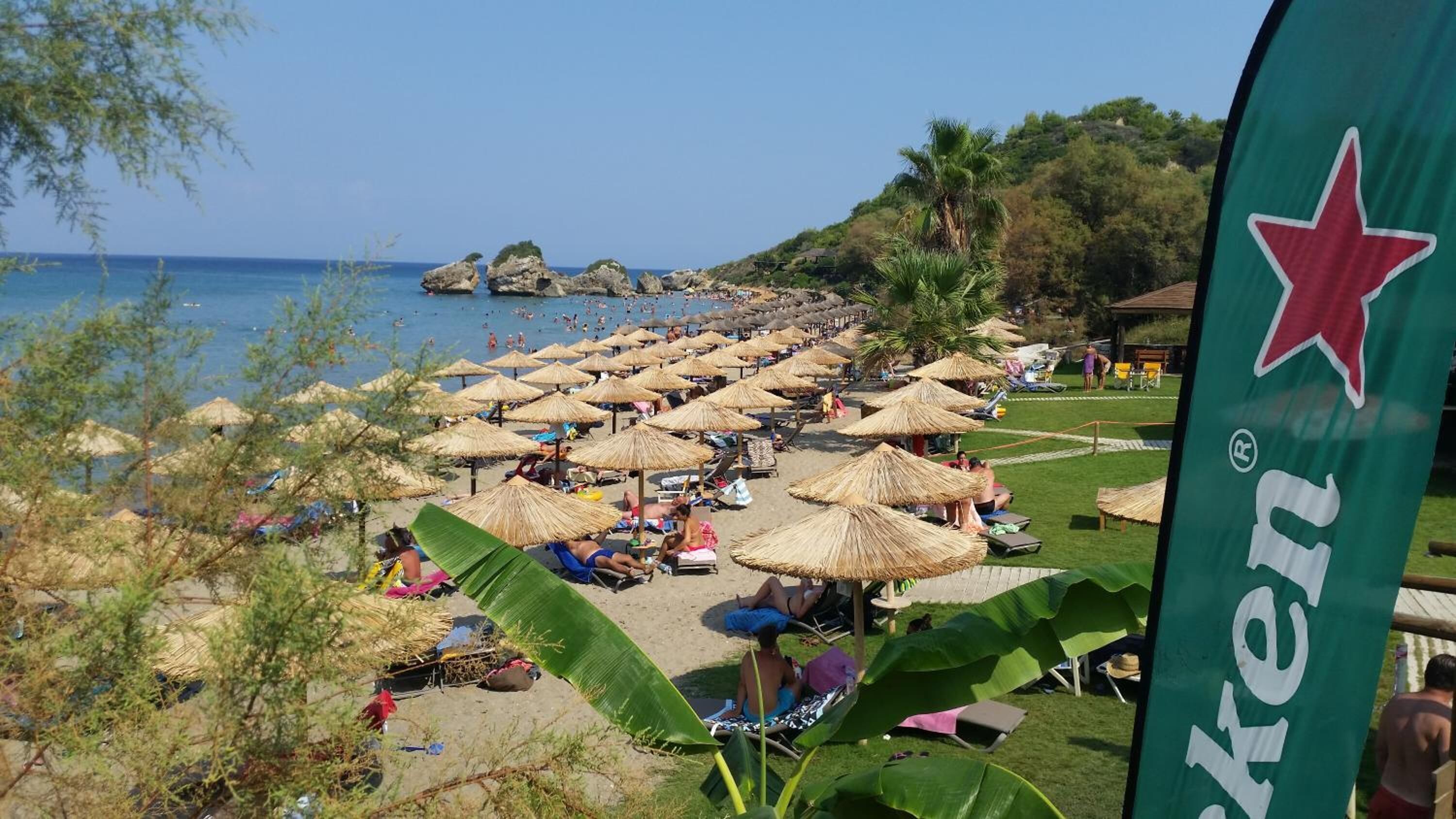 Ein Strand mit vielen Reetsonnenhütten und entspannenden Menschen.