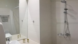 Un baño moderno con lavamanos, espejo y ducha.
