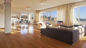 A spacious living room with a large sofa, a dining area with chairs, and a view of a historic site. - Impressive Apartment with Amazing Views in Athens City Centre! MK1 (Athens)