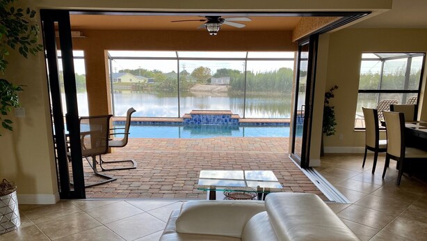 A living room with a large sliding glass door leading to a patio with a pool. - Southern Sun Beach Hotel - Cape Coral (Cape Coral)