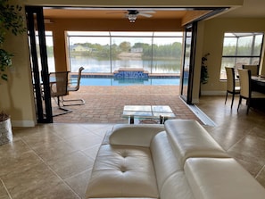 Ein Wohnzimmer mit einer großen Schiebeglastür, die auf eine Terrasse mit Pool führt.