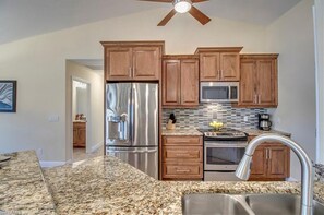 Enjoy cooking in this well-equipped kitchen with a granite countertop, stainless steel appliances, and wooden cabinetry.