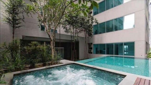 A modern building with a swimming pool and lush greenery. - Luxury Deluxe Studios At Mercu Summer Suites (Kuala Lumpur)