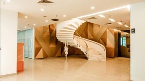 A modern interior with a spiral staircase, geometric wall patterns, and a clean, polished floor. - Luxury Deluxe Studios At Mercu Summer Suites (Kuala Lumpur)