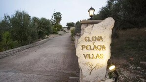 Een bordje voor Elena Pelaja Villas, met een lantaarnpaal en een pad.