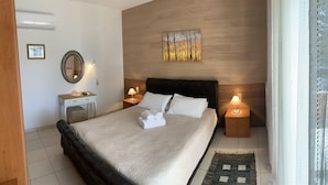 Een netjes ingerichte slaapkamer met een bed, nachtlampjes, een spiegel en een schilderij aan de muur.